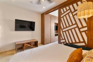 ein Schlafzimmer mit einem Bett und einem Fernseher an der Wand in der Unterkunft Paravian by Casago in Playa del Carmen