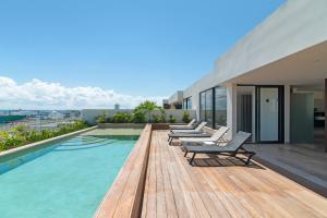 eine Terrasse mit Stühlen und ein Pool auf einem Gebäude in der Unterkunft Paravian by Casago in Playa del Carmen
