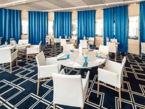 a conference room with white chairs and tables and blue curtains at Mercure Montpellier Centre Antigone in Montpellier
