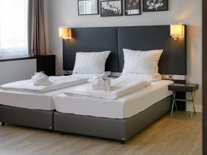 two beds in a room with white sheets and pillows at Mercure Hotel Potsdam City in Potsdam