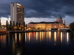 a city with a building on the water at night at Mercure Hotel Potsdam City in Potsdam