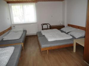 a room with three beds and a window at Turistická ubytovna Zámeček in Hojsova Stráž