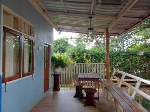 a porch with a wooden bench and a table at โฮมสเตย์ ยายหนั่น in Ban Nong Kham Tai