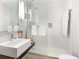 a white bathroom with a sink and a tub at Mercure Napoli Centro Angioino in Naples +68 photos