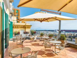 a patio with tables and chairs and umbrellas at Mercure Napoli Centro Angioino in Naples