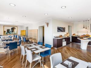 a restaurant with white tables and blue chairs at Mercure Napoli Centro Angioino in Naples