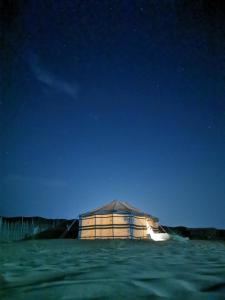 Un pequeño edificio en medio del agua por la noche. en Arabian Desert nights, en Badīyah