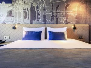 a bedroom with a bed with two blue pillows at Mercure Budapest Castle Hill in Budapest