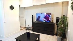un salon avec une télévision à écran plat et une table dans l'établissement Fresh And Cozy Little House 30km In Täby, à Stockholm 5 autres photos