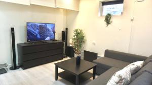 un salon avec un canapé et une télévision à écran plat dans l'établissement Fresh And Cozy Little House 30km In Täby, à Stockholm