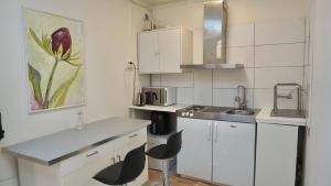 une petite cuisine avec des armoires blanches et un évier dans l'établissement Fresh And Cozy Little House 30km In Täby, à Stockholm