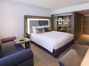 een hotelkamer met een groot bed en een bank bij Novotel Bangkok Bangna in Bangna