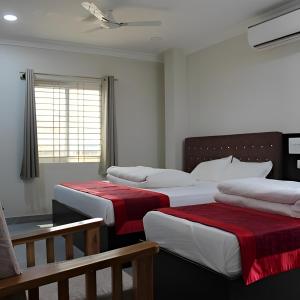 a bedroom with three beds with red and white sheets at SRG Shivam Residency in Tiruvannāmalai