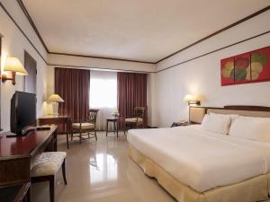 a hotel room with a large bed and a desk at Mercure Chiang Mai in Chiang Mai +80 photos