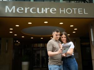un hombre y una mujer parados frente a un hotel en Mercure Budapest Korona, en Budapest