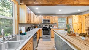 Una cocina con gabinetes de madera y electrodomésticos de acero inoxidable. en Sweet Pine Deck Hot Tub Cozy Modern Interior Close to Ski Resort, en Pomins