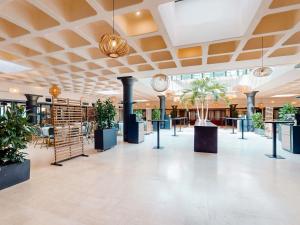 Un vestíbulo con plantas en macetas en un edificio. en Mercure Bordeaux Chateau Chartrons, en Burdeos