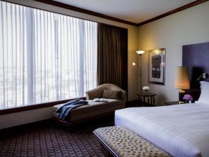 a hotel room with a bed and a chair and a window at Pullman Khon Kaen Raja Orchid in Khon Kaen