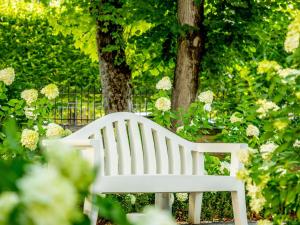una panchina bianca in un giardino fiorito di Hotel De Bourbon Grand Hotel Mercure Bourges a Bourges