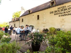 un gruppo di persone seduti a un tavolo di fronte a un edificio di Hotel De Bourbon Grand Hotel Mercure Bourges a Bourges