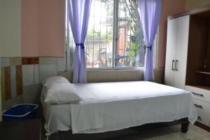 Schlafzimmer mit einem Bett und einem Fenster mit lila Vorhängen in der Unterkunft Casa Albacora in Puerto Baquerizo Moreno