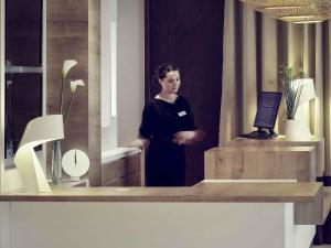 Eine Frau steht vor einem Spiegel in der Unterkunft Mercure Hotel Forbach Centre de Loisirs in Forbach