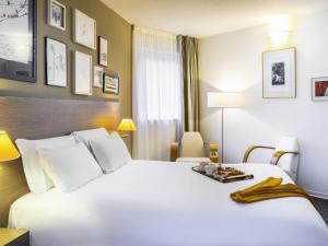 ein Hotelzimmer mit zwei Betten und einem Tisch in der Unterkunft Mercure Hotel Forbach Centre de Loisirs in Forbach