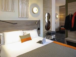 a bedroom with a white bed with a clock on the wall at Mercure Hotel Forbach Centre de Loisirs in Forbach +137 photos