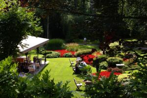 un jardín con mesas, sillas y flores en Hotel de la Gaichel, en Eischen