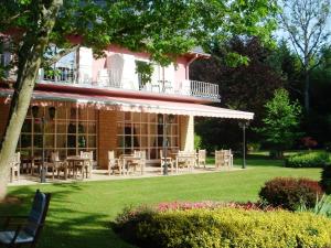 a building with tables and chairs in a yard at Hotel de la Gaichel in Eischen