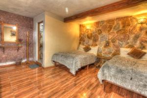 a bedroom with two beds and a stone wall at Hotel Posada El Camino in Chignahuapan