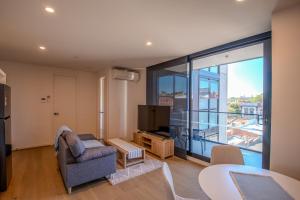 a living room with a couch and a television at Cosy 1 Bedroom Studio Hawthorn near Swinburne Uni in Melbourne