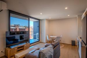 a living room with a couch and a large screen tv at Cosy 1 Bedroom Studio Hawthorn near Swinburne Uni in Melbourne