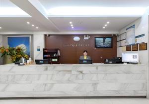 una donna seduta al bancone di una hall di City Comfort Inn Wuhan Jiefang Avenue Xinrong Light Rail Station a Wuhan