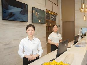 two women standing in a kitchen with a counter at City Comfort Inn Suzhou Wujiang Development Zone Yundong in Suzhou