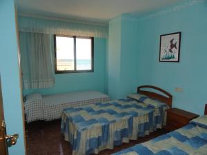 a blue bedroom with two beds and a window at Apartamentos Raymar in Oropesa del Mar