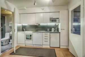 una cocina con armarios blancos y electrodomésticos en una habitación en Vanhan Karhun Huoneistot, en Ruka