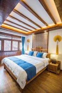 a bedroom with a large bed with blue and white sheets at Lijiang Yue Tu Inn in Lijiang