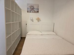 a small bedroom with a white bed and shelves at La Casa di Maty in Reggio Calabria