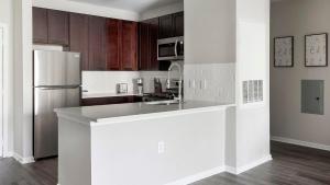 La cuisine est équipée d'un comptoir blanc et d'un réfrigérateur. dans l'établissement Landing Beautiful 2BD Clubhouse Gym, à Betzwood