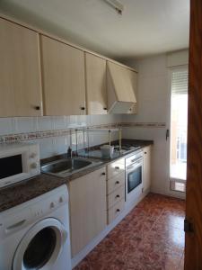 a kitchen with a sink and a washing machine at Apartamentos Raymar in Oropesa del Mar +32 photos
