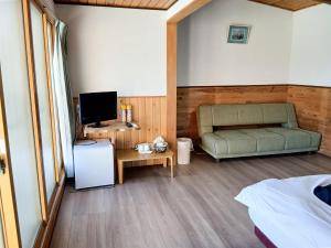 a bedroom with a couch and a tv in a room at olive no sato vingh four eyes shodoshima - Vacation STAY 38568v in Kusakabe