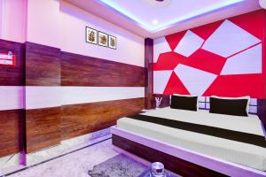 a bedroom with a bed with a red and white wall at Super Collection O New Jalpaiguri Railway Station Formerly Prince Lodge in Siliguri +23 photos