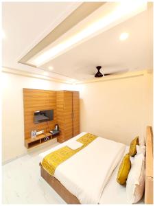 a bedroom with a bed and a tv on the wall at HOTEL BNK GRAND Near Goḏawalia Chauraha - 100 Meter From Baba Vishwanath Temple & Ganga Arti Ghat ! Wi-Fi #Lift #Hygiene & Spacious Room - BEST HOTEL IN VARANASI in Varanasi +18 photos