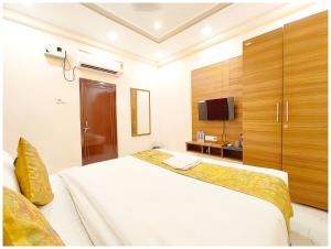 una camera con un grande letto bianco e una TV di HOTEL BNK GRAND Near Goḏawalia Chauraha - 100 Meter From Baba Vishwanath Temple & Ganga Arti Ghat ! Wi-Fi #Lift #Hygiene & Spacious Room - BEST HOTEL IN VARANASI a Varanasi