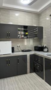 a kitchen with black cabinets and a white counter top at Pat deluxe in New Weija