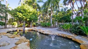 Cottage by the Pool by AvantStay w Balcony BBQ Shared Pool Month Long Stays Only في ستوك آيلاند: بركة مع نافورة في ساحة بها أشجار