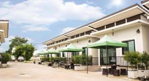 un edificio con sombrillas verdes delante en Thongsuk Mini Resort, en Pran Buri