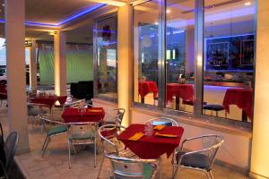 a restaurant with red tables and chairs in front of a window at Hotel Ariston in Marina di Grosseto +11 photos