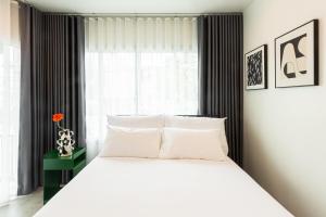 a bedroom with a white bed and a window at anhaus chiangrai in Chiang Rai